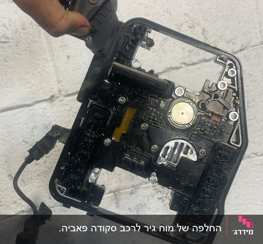 חלק מכני מוחזק ביד על רקע קיר לבן